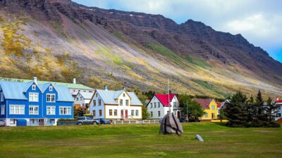 A little town at the center of a fjord with brightly painted houses and mountains behind