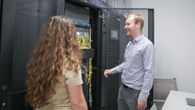 Computer Science professor showing a student a networking rack in the server room.