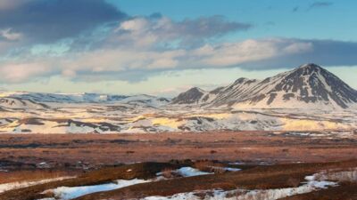Flat plains in front of barren rocky mountains in Akureyri