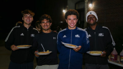 Four students outside at night eating waffles