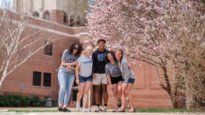 Five students laughing together in a group photo with Weller tower in the background