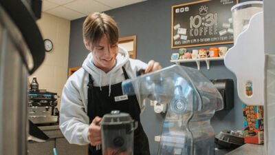 Student worker at the 10:31 coffee shop, ready to take an order.