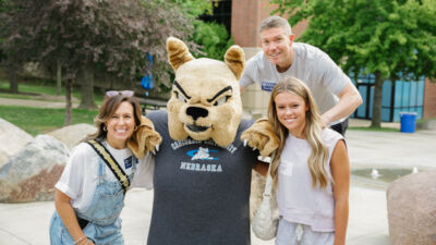 A new student and her parents posing with Bruiser the Bulldog