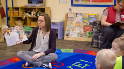 A Concordia student reading a picture book to children at St. John's Child Development Center