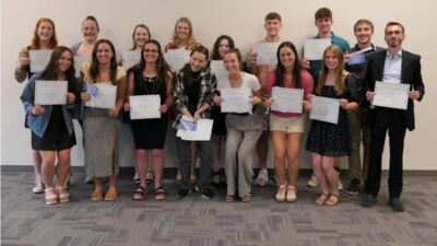 A group of students holding certificate awards smile at the camera.