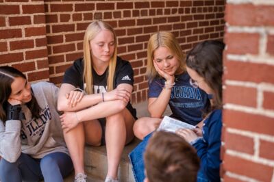 Students sitting on some steps reading the Bible.
