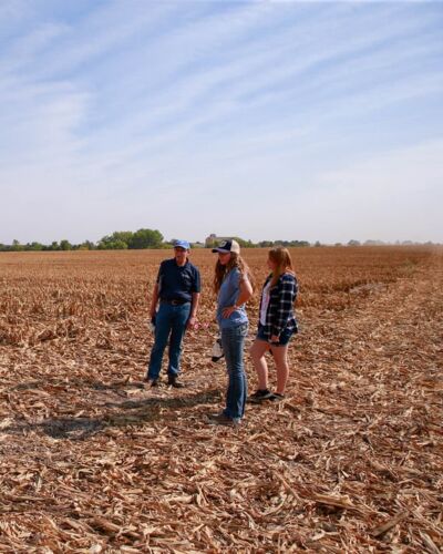 Ag Science Professor Dr. Dennis Brink with two students surveying a corn field. 
