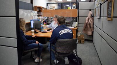 Two students reviewing information with a Student Financial Aid staff member. 