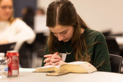 A woman praying at a group bible study. 