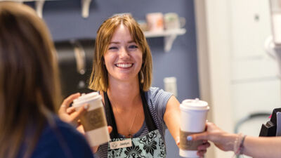 A student handing out coffee at 10:31 Coffee House